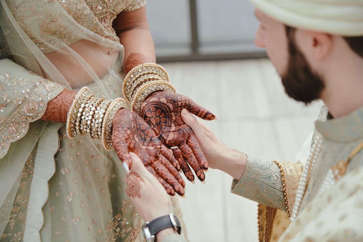 Close-up of intricate henna design on bride's hands during Indian wedding ceremony.