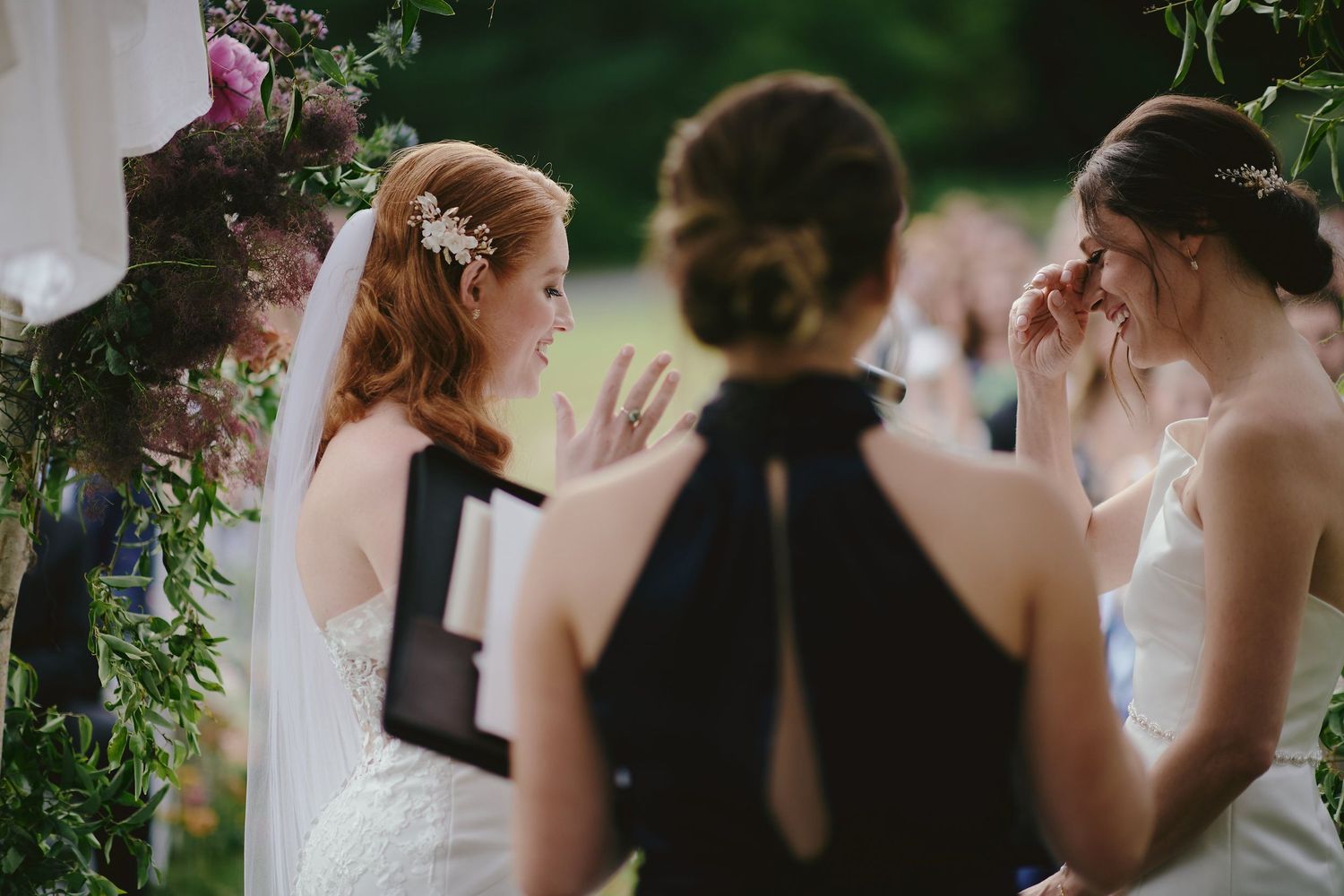 Wedding party gathered under floral archway during an outdoor garden ceremony.