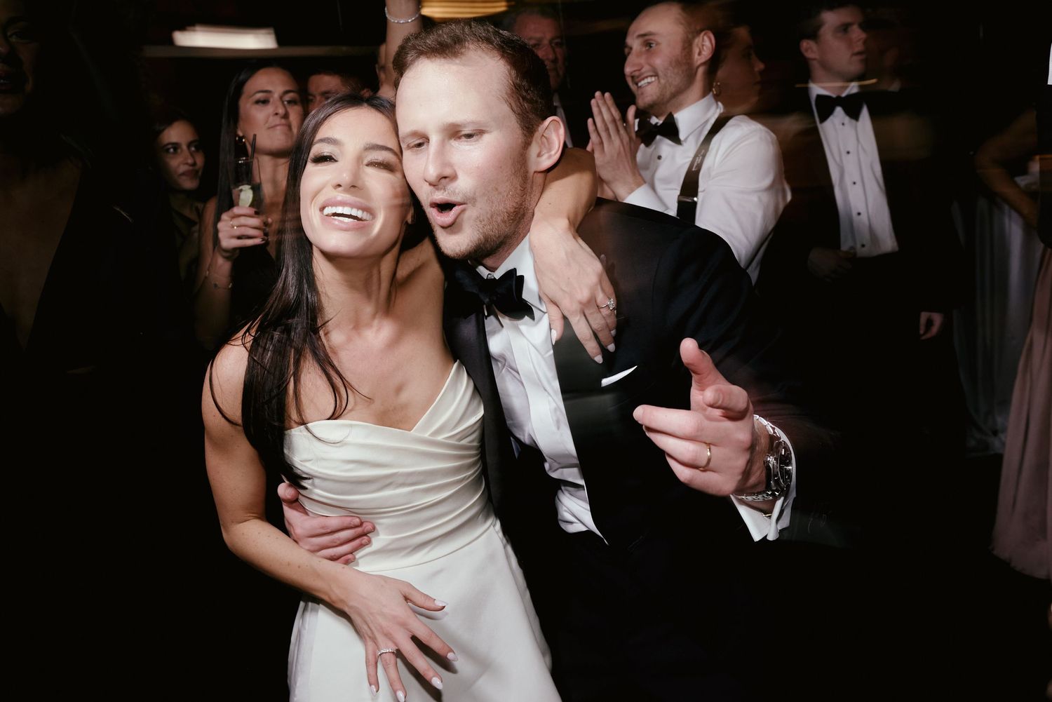 A couple in formal attire dancing and laughing together at an elegant evening reception.