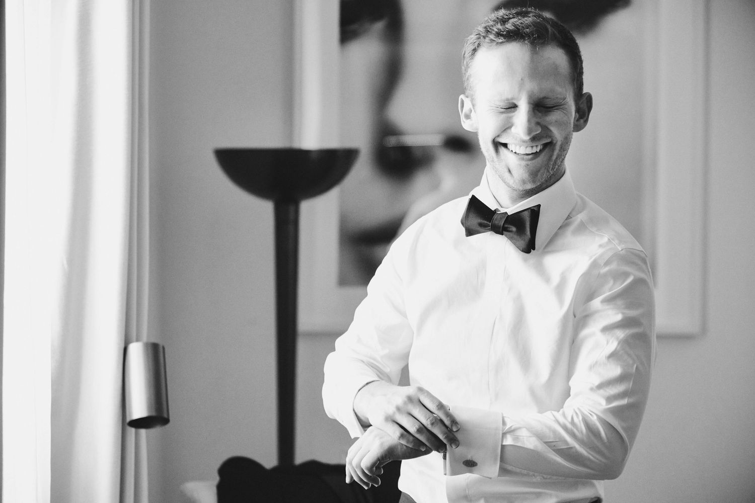 Black and white portrait of a smiling person wearing a crisp white dress shirt and black bow tie.