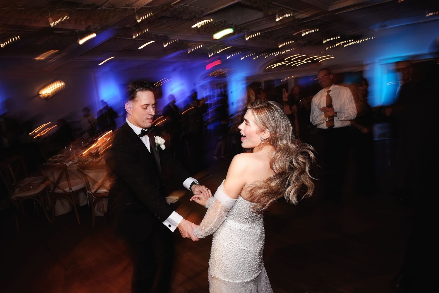 A couple dances at their wedding reception with motion-blurred lights creating a dreamy atmosphere.