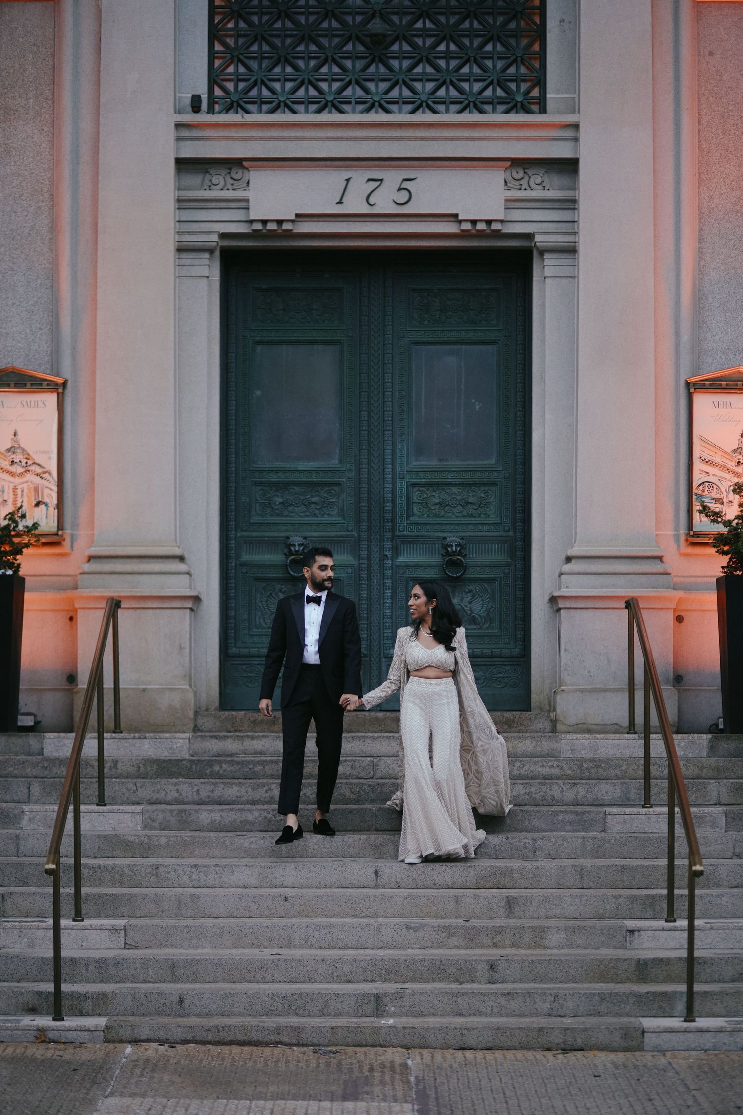 Elegant couple posing on historic building steps with large green door numbered 175.