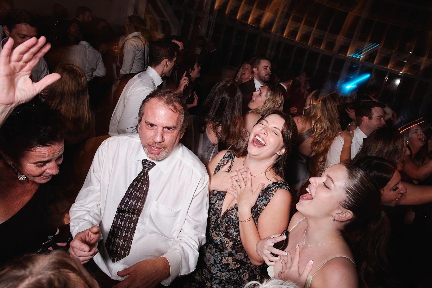 Party guests dancing and laughing together at a crowded nighttime celebration event.