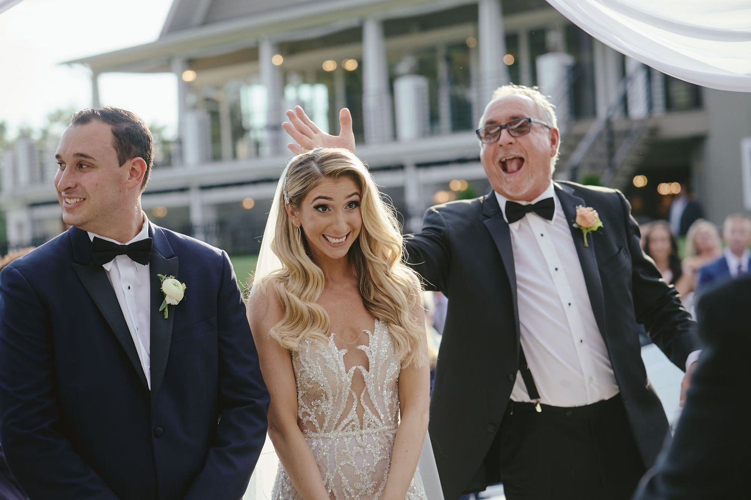 Wedding party shares a candid laughing moment outdoors during formal celebration.