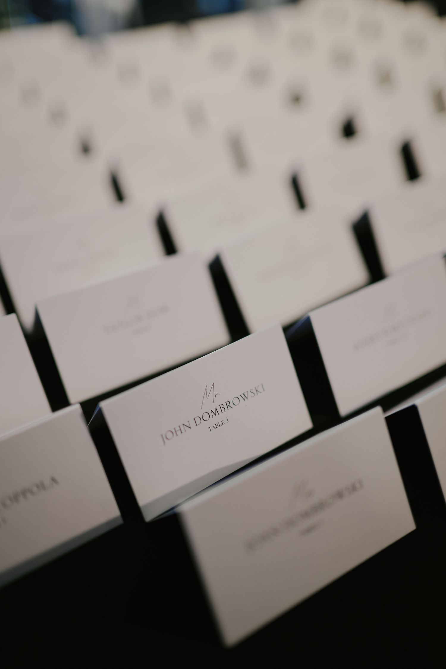 White place cards arranged on a dark surface for formal event seating, with guest names printed in elegant text.