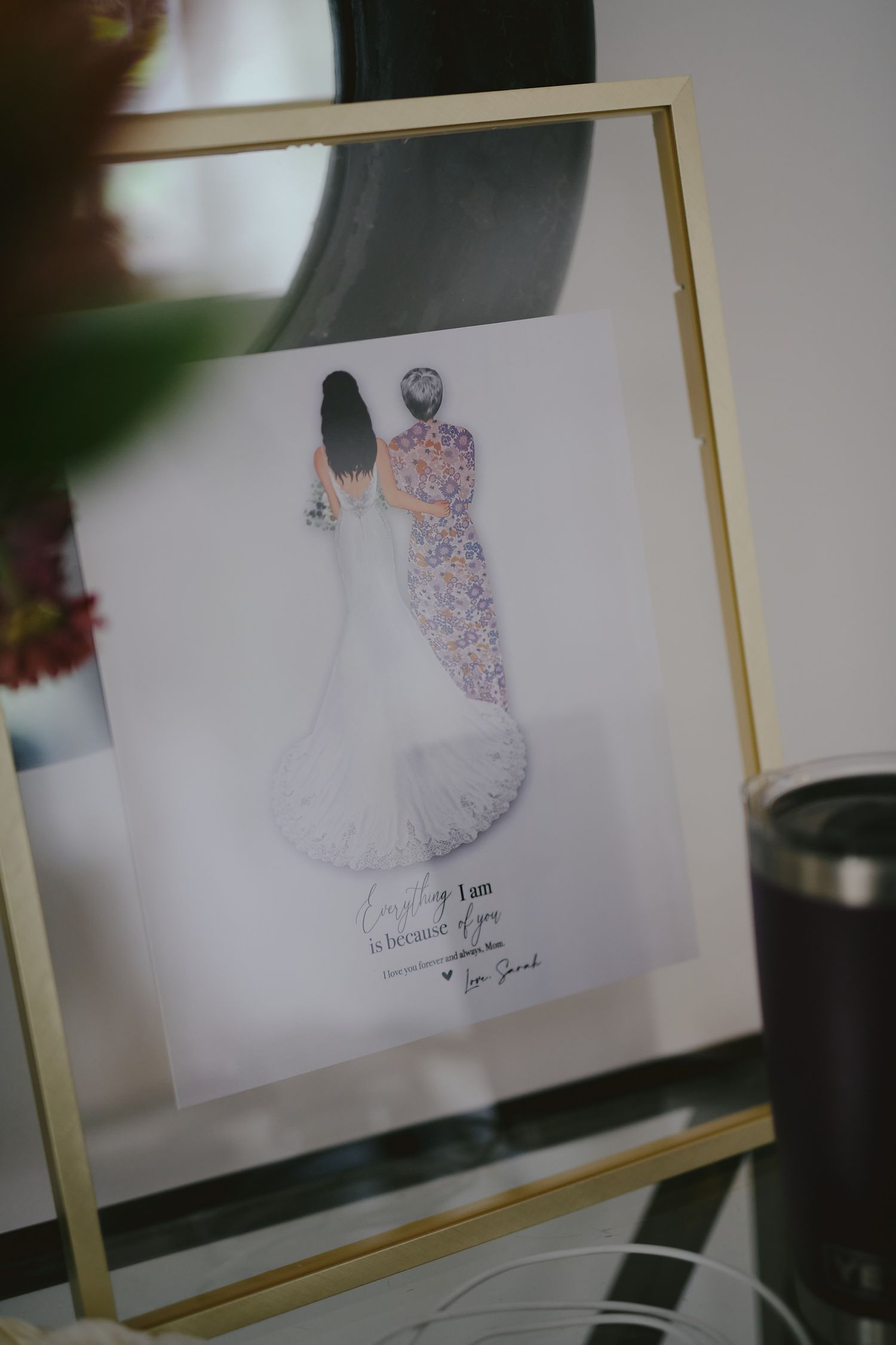 A framed fashion illustration showing a delicate sketch of a figure in a flowing dress with floral pattern details.