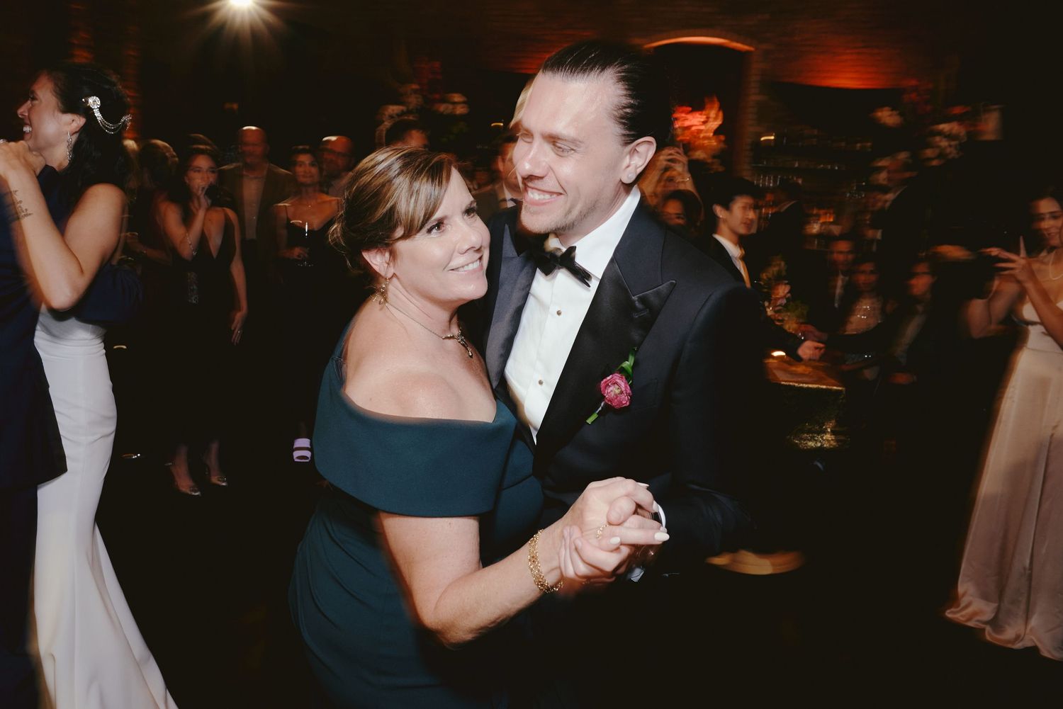 A couple shares an intimate dance moment at an elegant evening reception with dim lighting and formal attire.