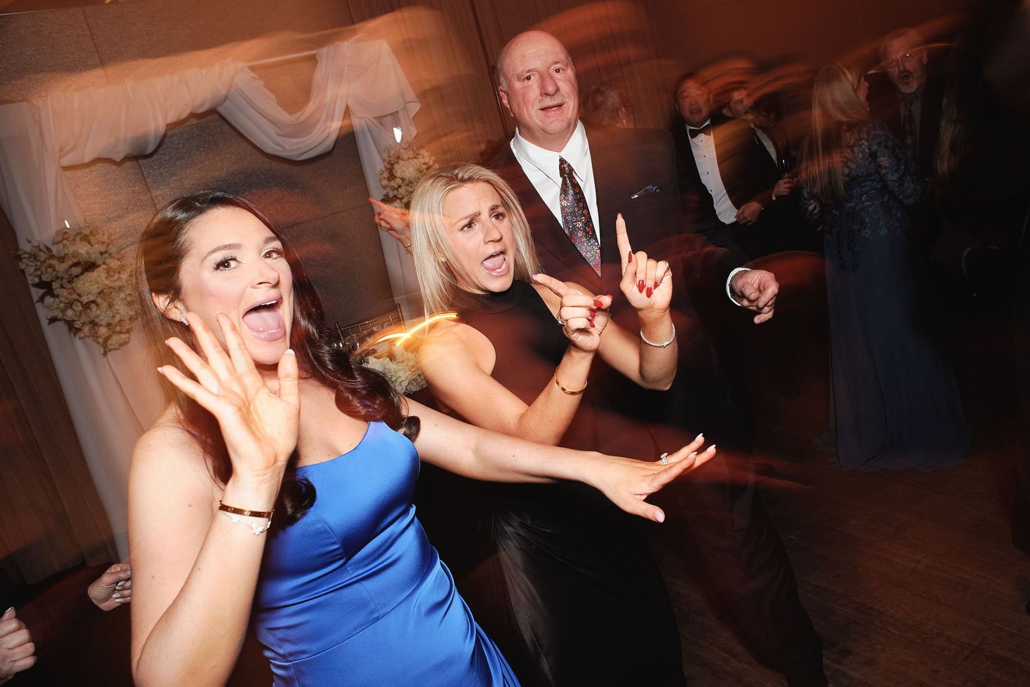 People dancing and having fun at a party, with energetic expressions and lively movement on the dance floor.