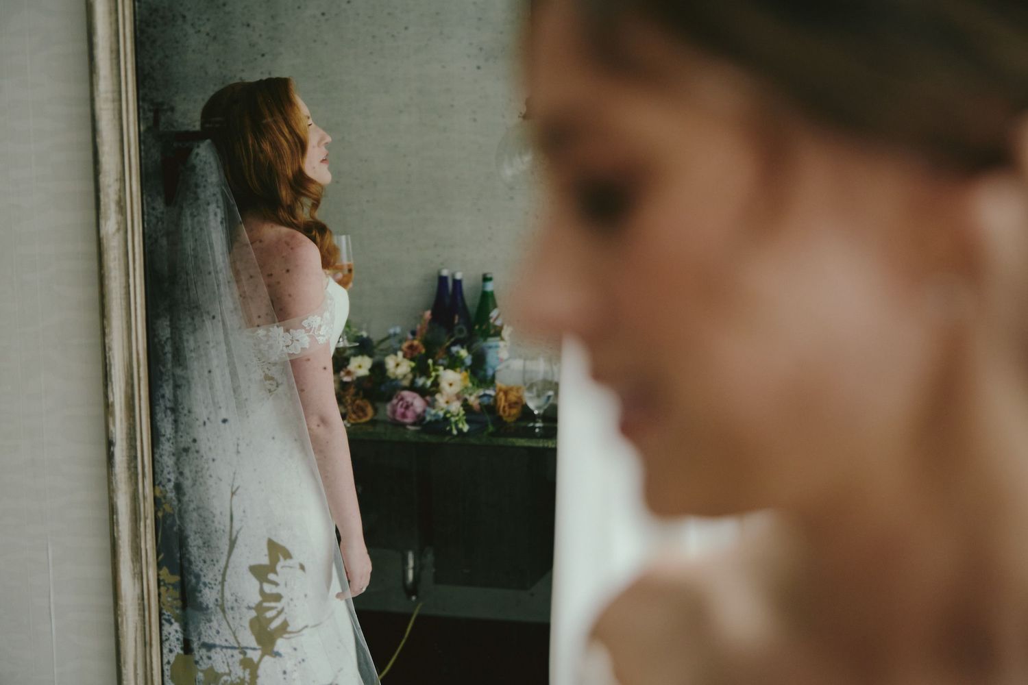 Two elegant white wedding dresses with lace details shown in a stylized bridal preparation scene.