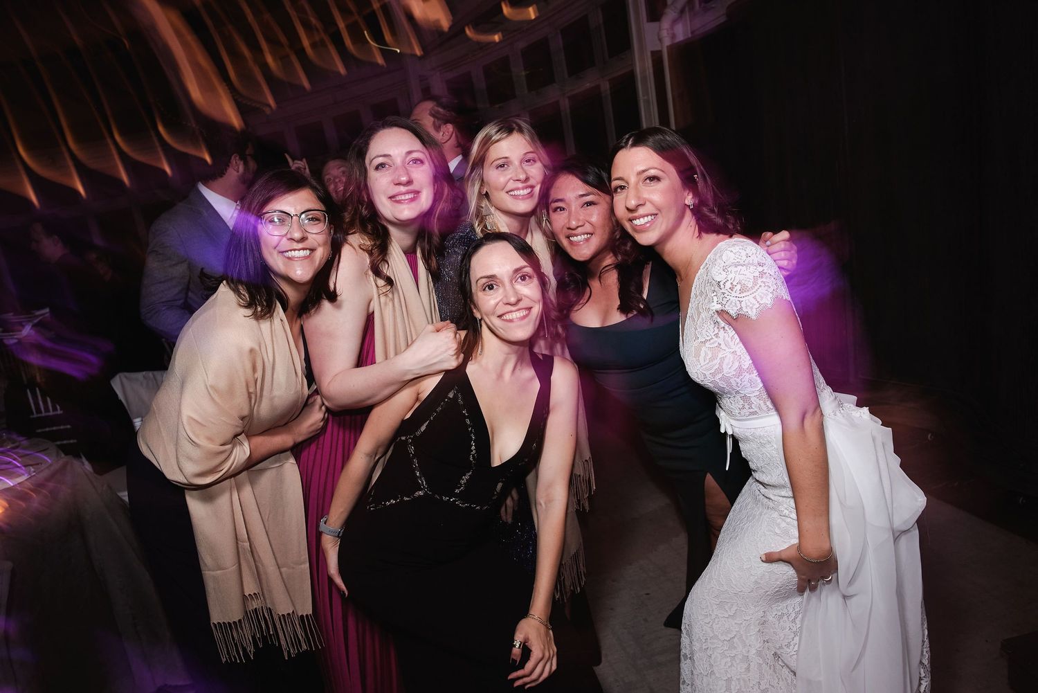 A group of friends enjoying themselves at a nighttime celebration with purple lighting in the background.