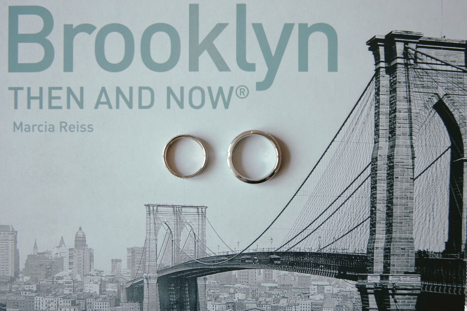 Wedding rings placed on a black and white coffee table book featuring the Brooklyn Bridge and New York City skyline.