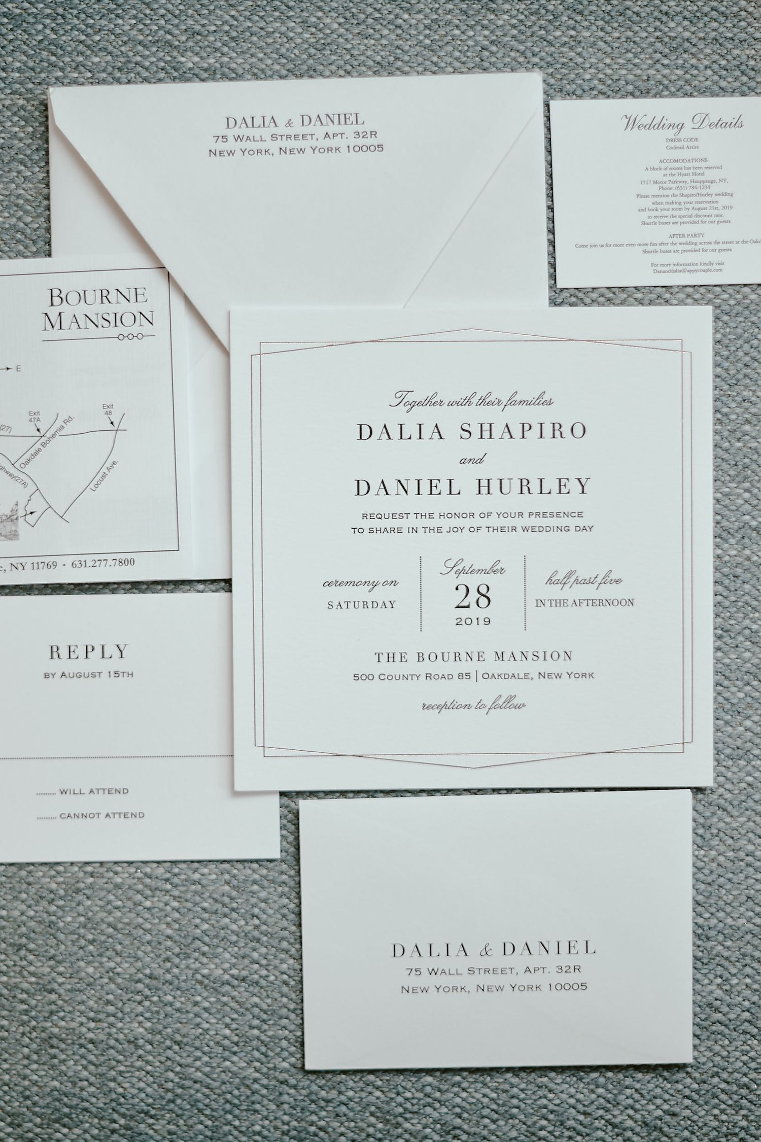 Elegant white and gray wedding invitation suite with venue map and details for The Bourne Mansion displayed on textured fabric.