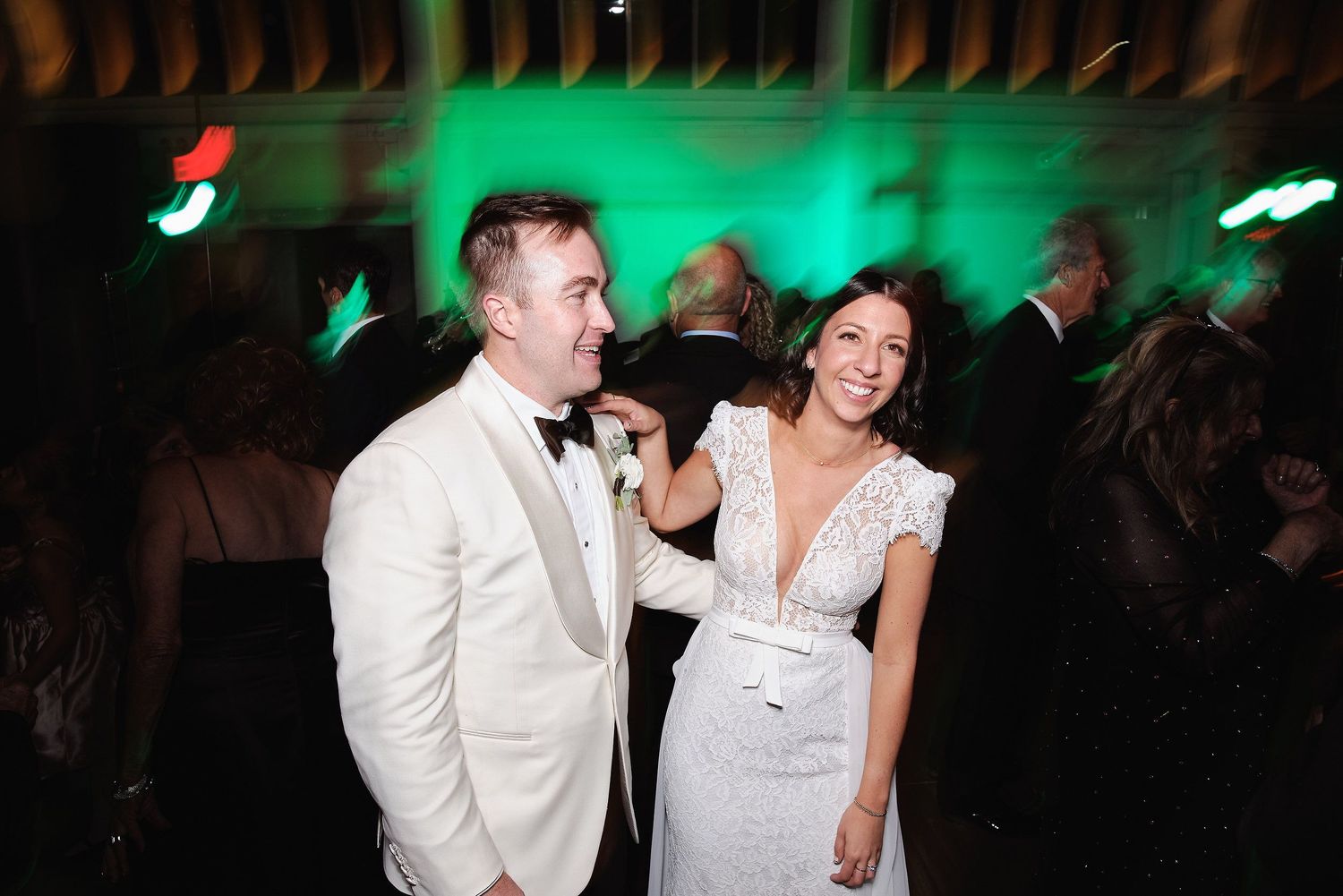 People enjoying a lively moment on a dance floor with green lighting in the background.