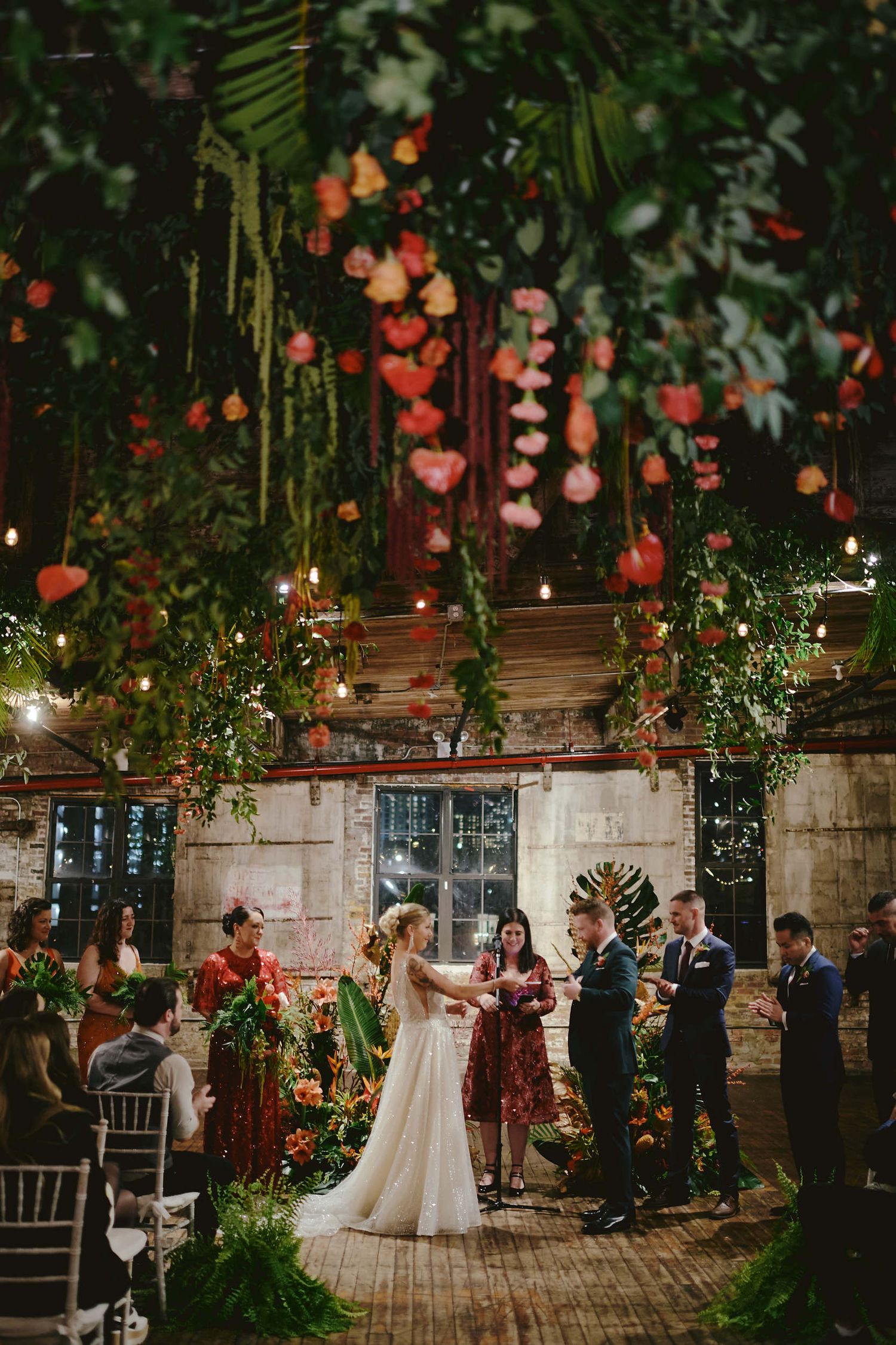 A romantic indoor venue decorated with hanging flowers, twinkling lights and greenery for an enchanting wedding ceremony.