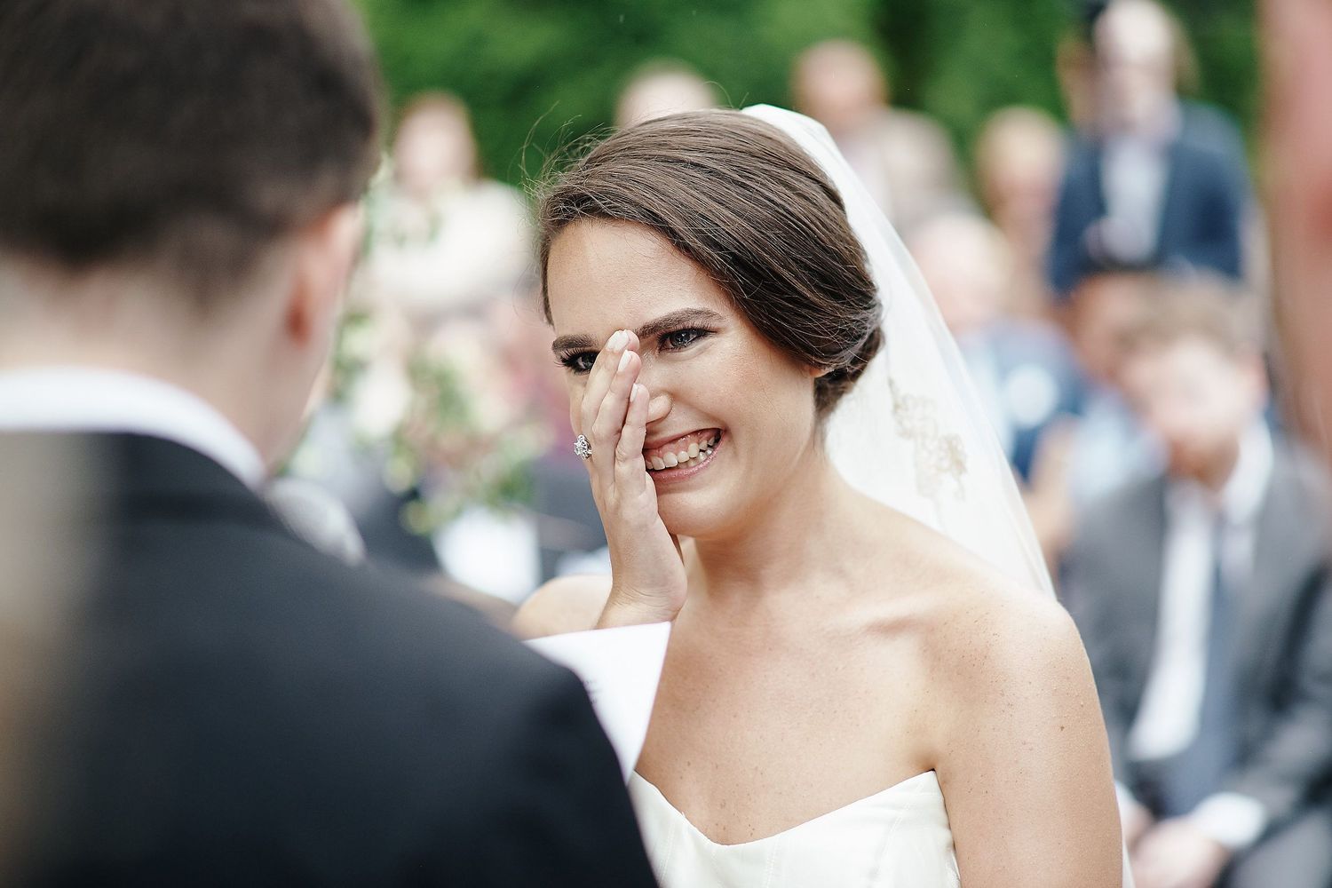 A candid moment of joy and laughter during a wedding ceremony in a garden setting.