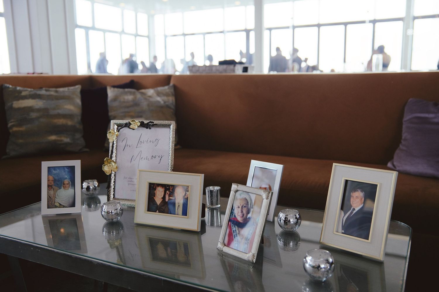 Collection of framed family photos displayed on glass table at wedding reception.