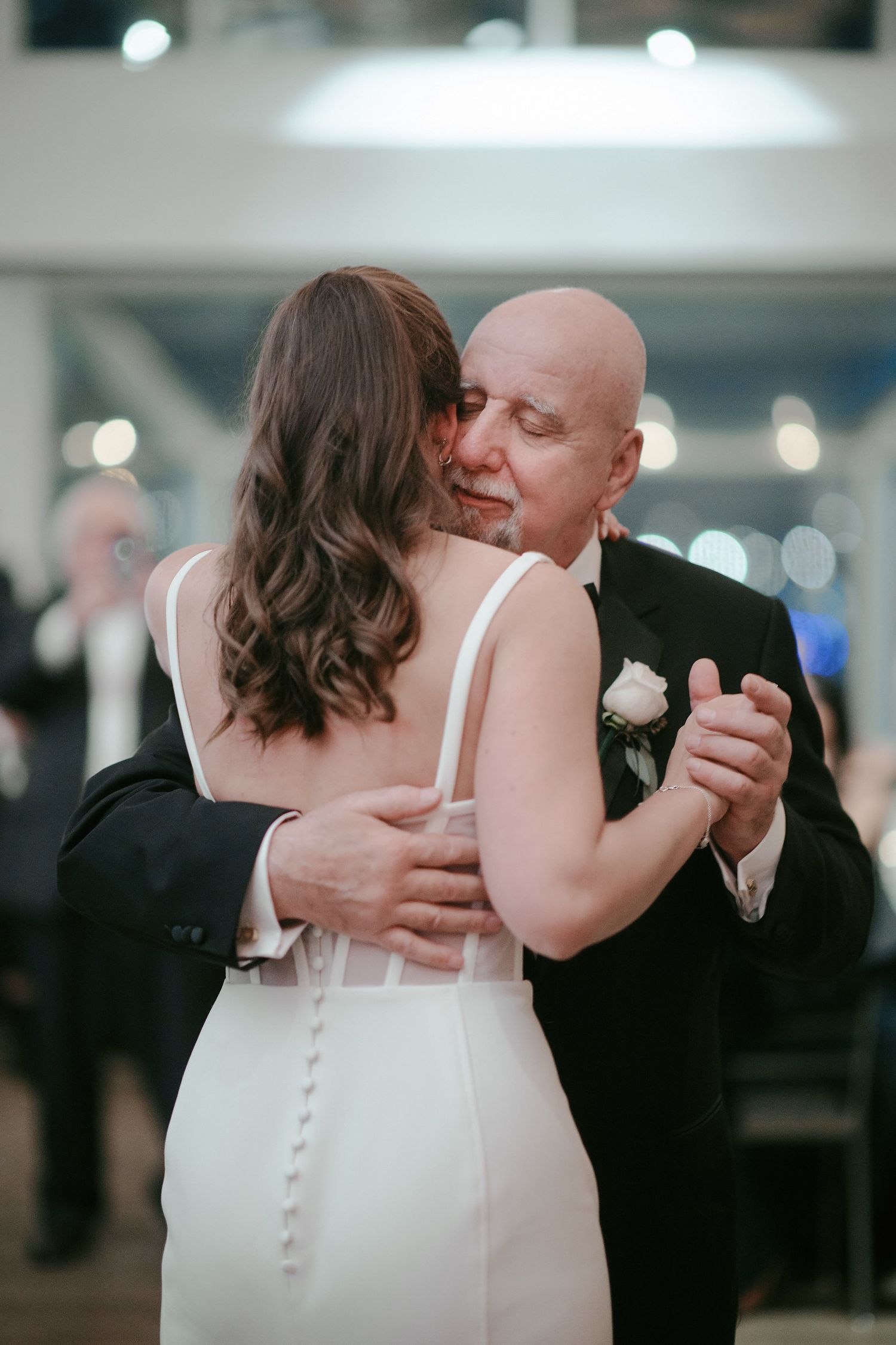 A tender dance embrace between a bride in a white gown and her partner during their wedding reception.