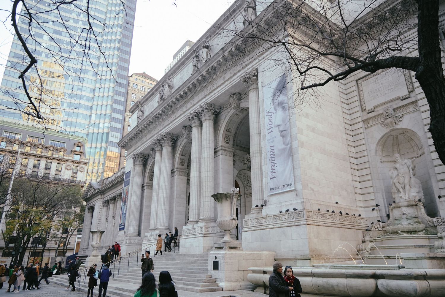 People gather on the steps of the historic New York Public Library building with its iconic Beaux-Arts columns and architecture.