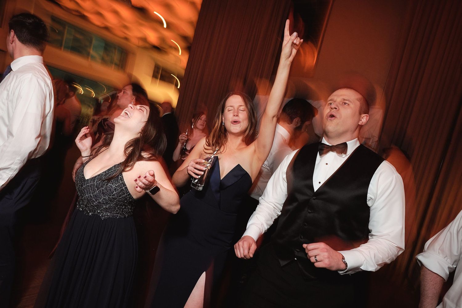 Party guests dance and celebrate enthusiastically on the dance floor at an elegant formal event.