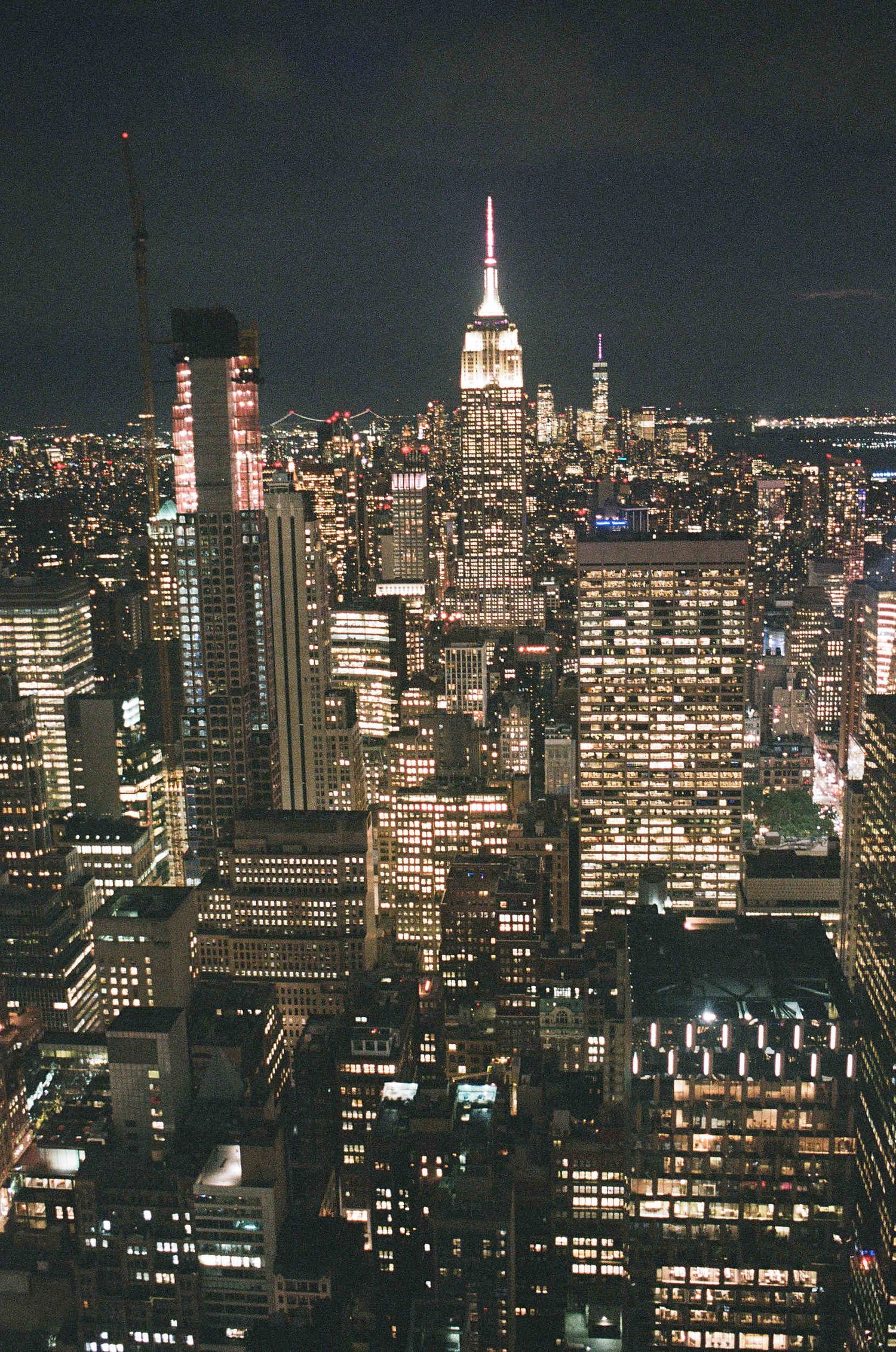 Illuminated Empire State Building and Manhattan skyline at night with glowing city lights.