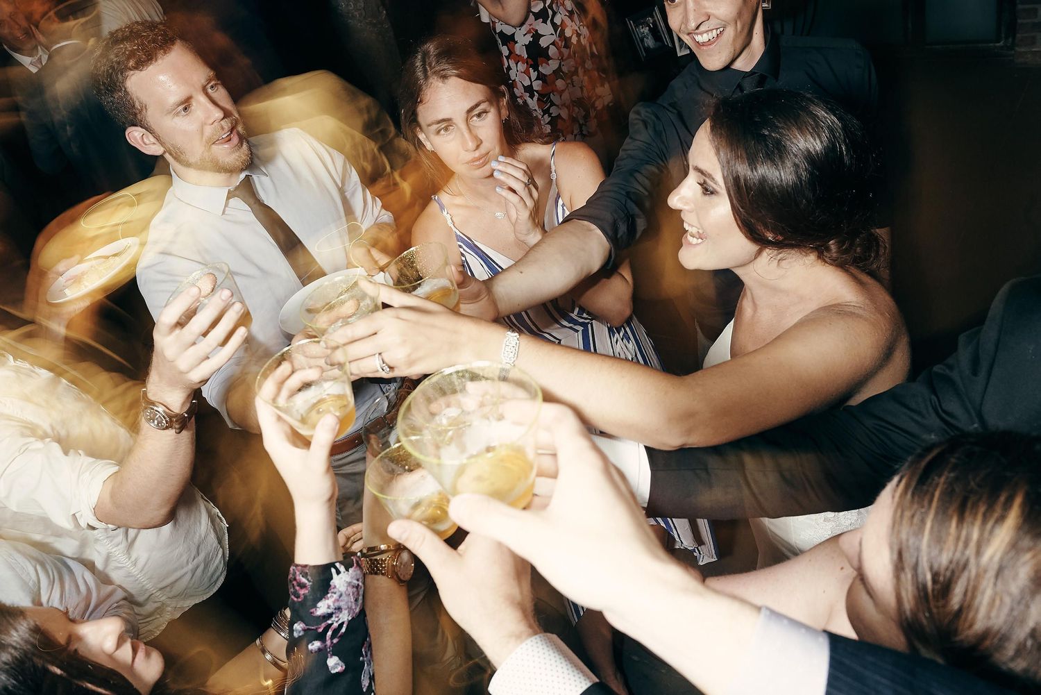 Group of wedding guests reaching for bread and sharing appetizers at celebration dinner.