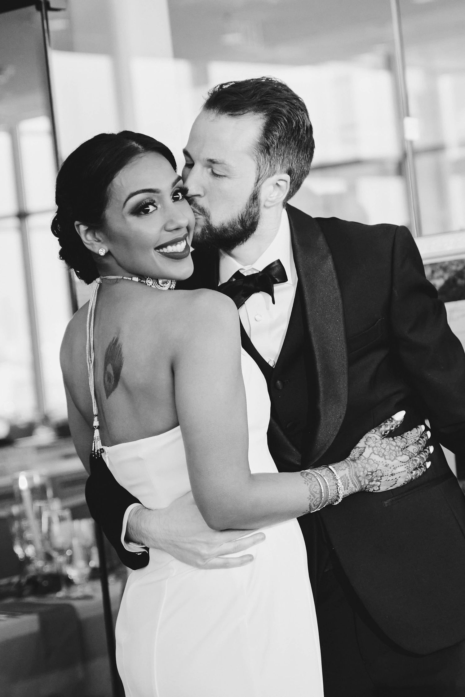 Black and white photo of a romantic moment between newlyweds in formal wedding attire.