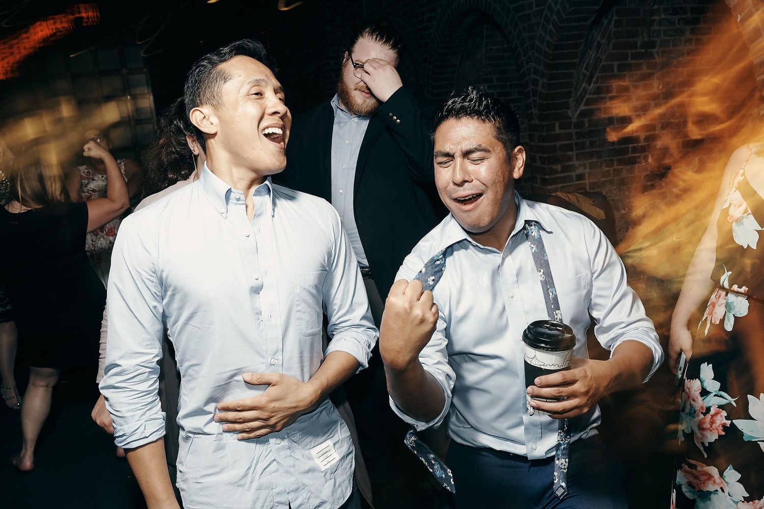 Two party guests in white shirts enthusiastically dancing and singing together at a lively celebration.
