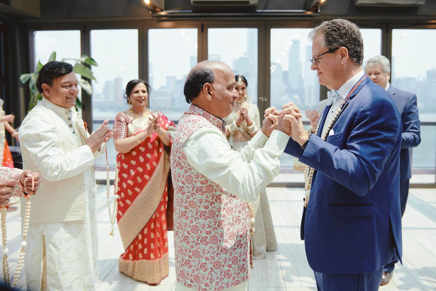People celebrating at an event in formal attire share a joyful moment while dancing in a bright indoor space.