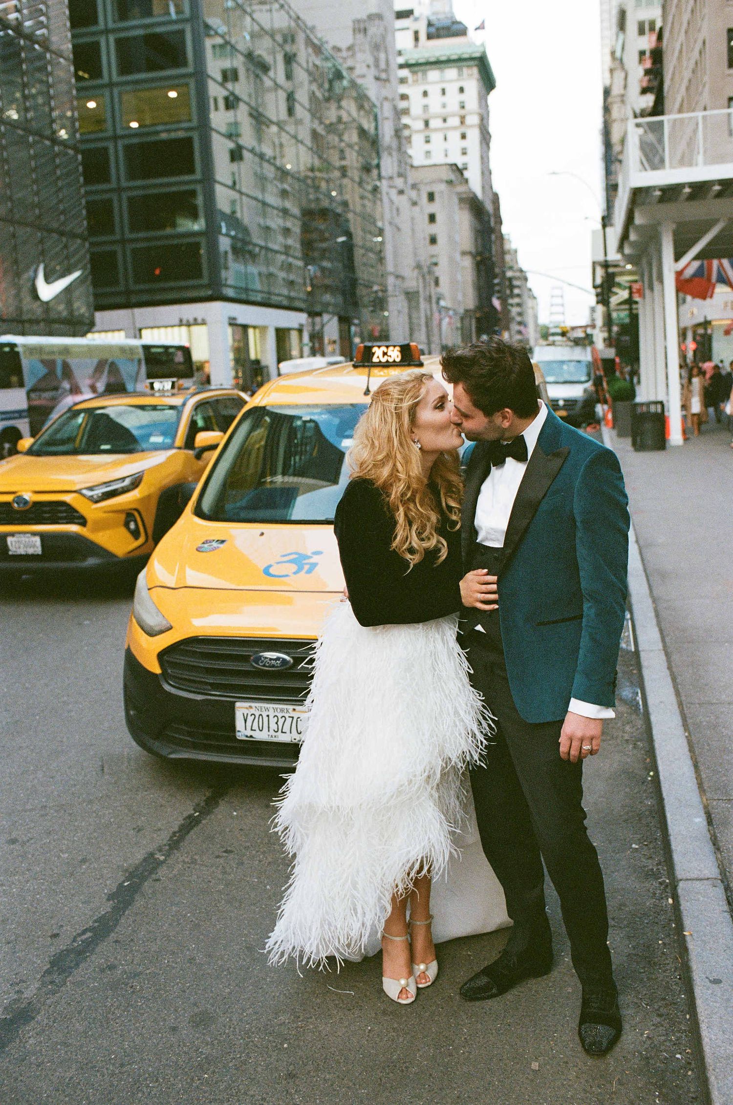 Stylish couple poses together on NYC street with yellow taxi in background.
