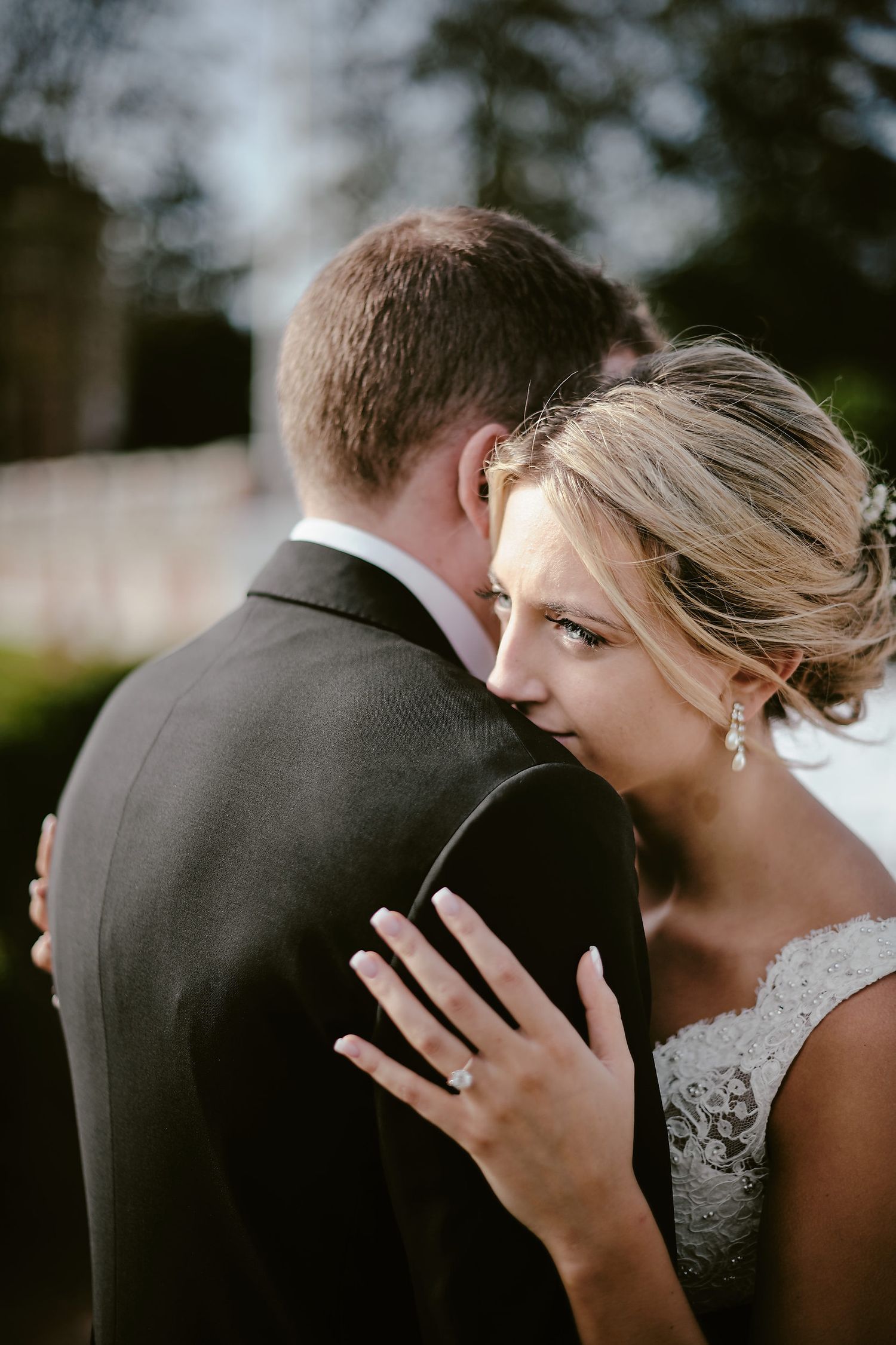 An intimate wedding portrait shows a tender moment between newlyweds with the bride's hand resting on the groom's back.