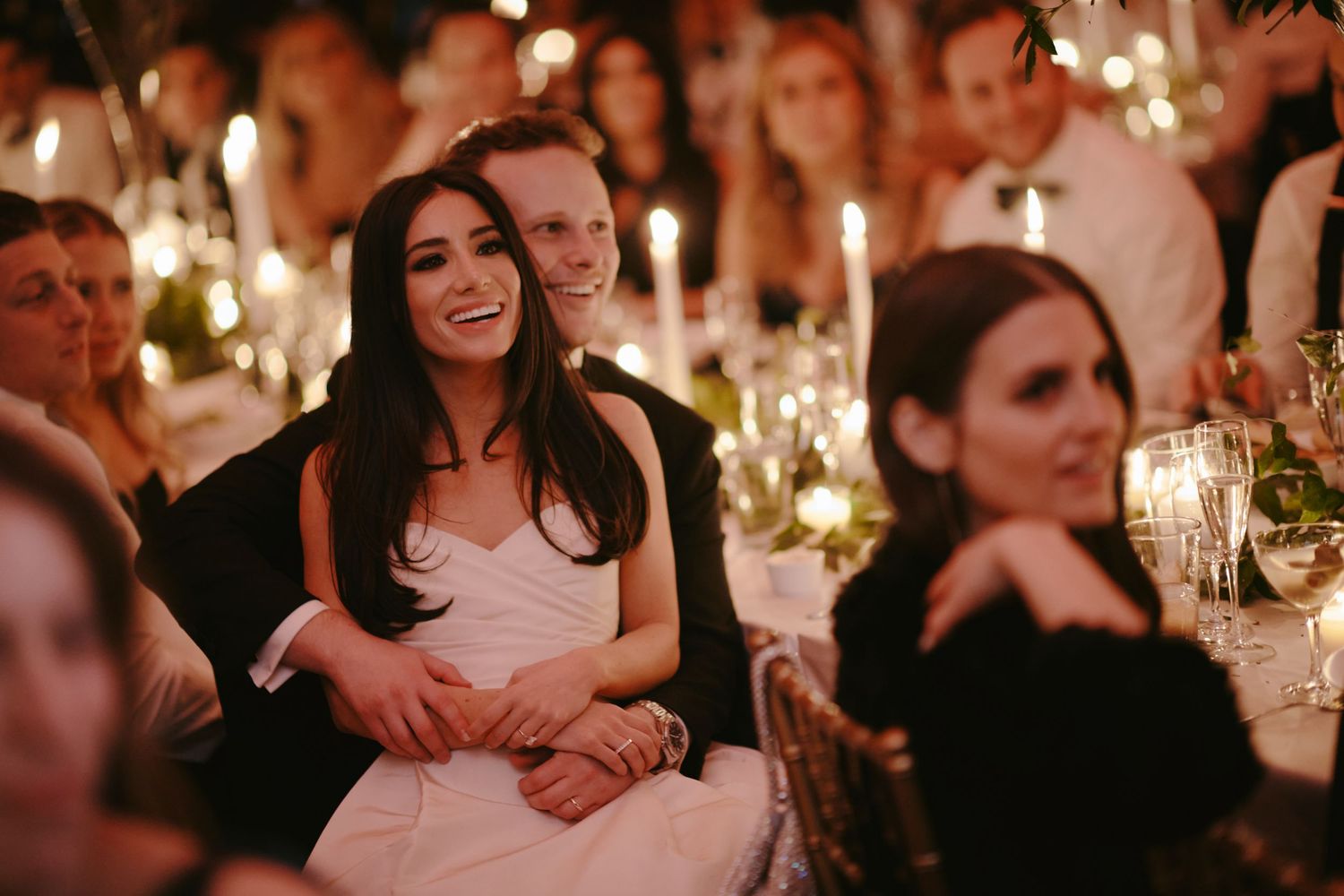 Guests enjoying a candlelit wedding reception dinner with tables decorated with glowing centerpieces.