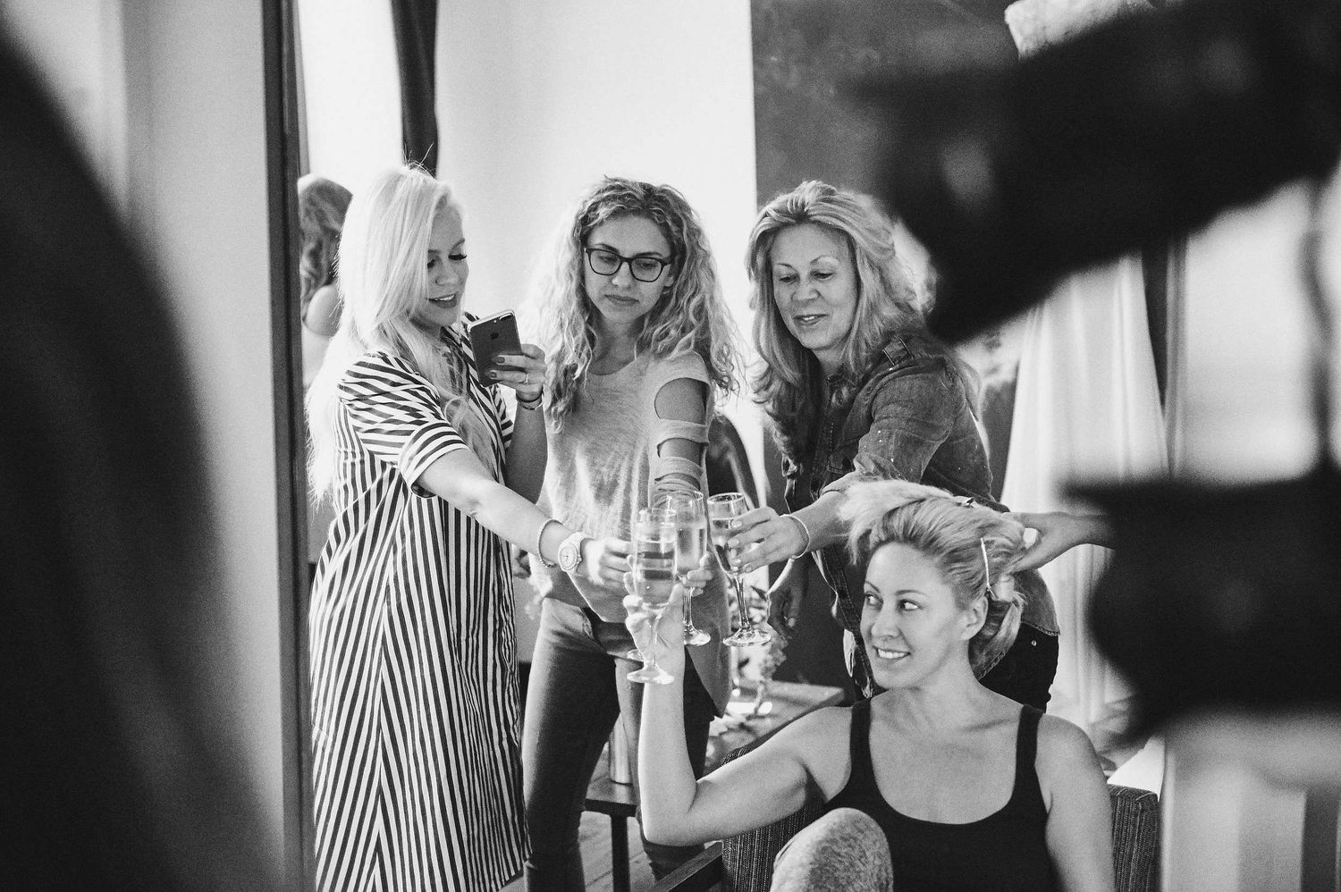 Black and white photo showing a group of people gathered together sharing drinks and socializing at an event.