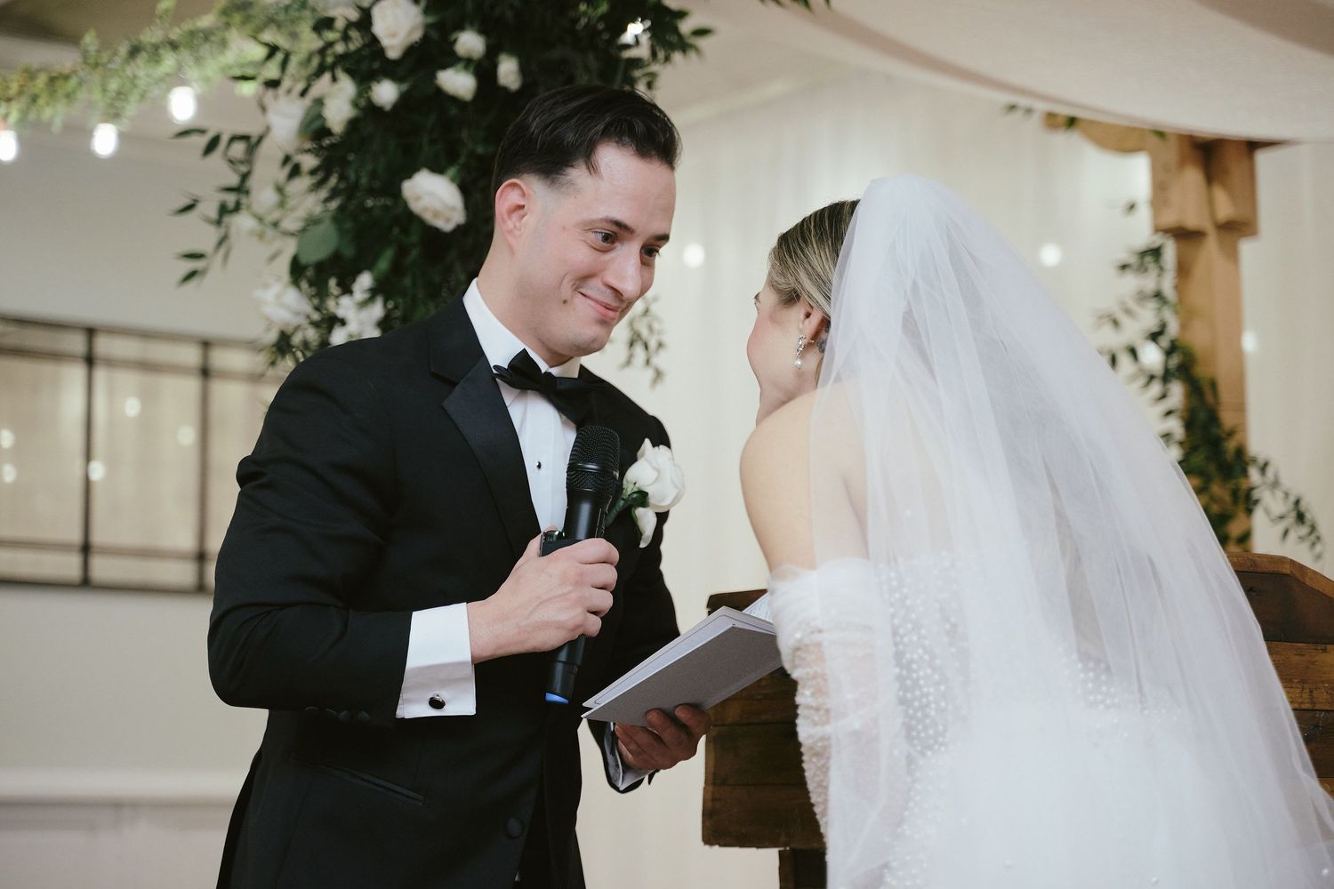 A couple shares an intimate moment during their wedding ceremony while exchanging vows in an indoor venue.