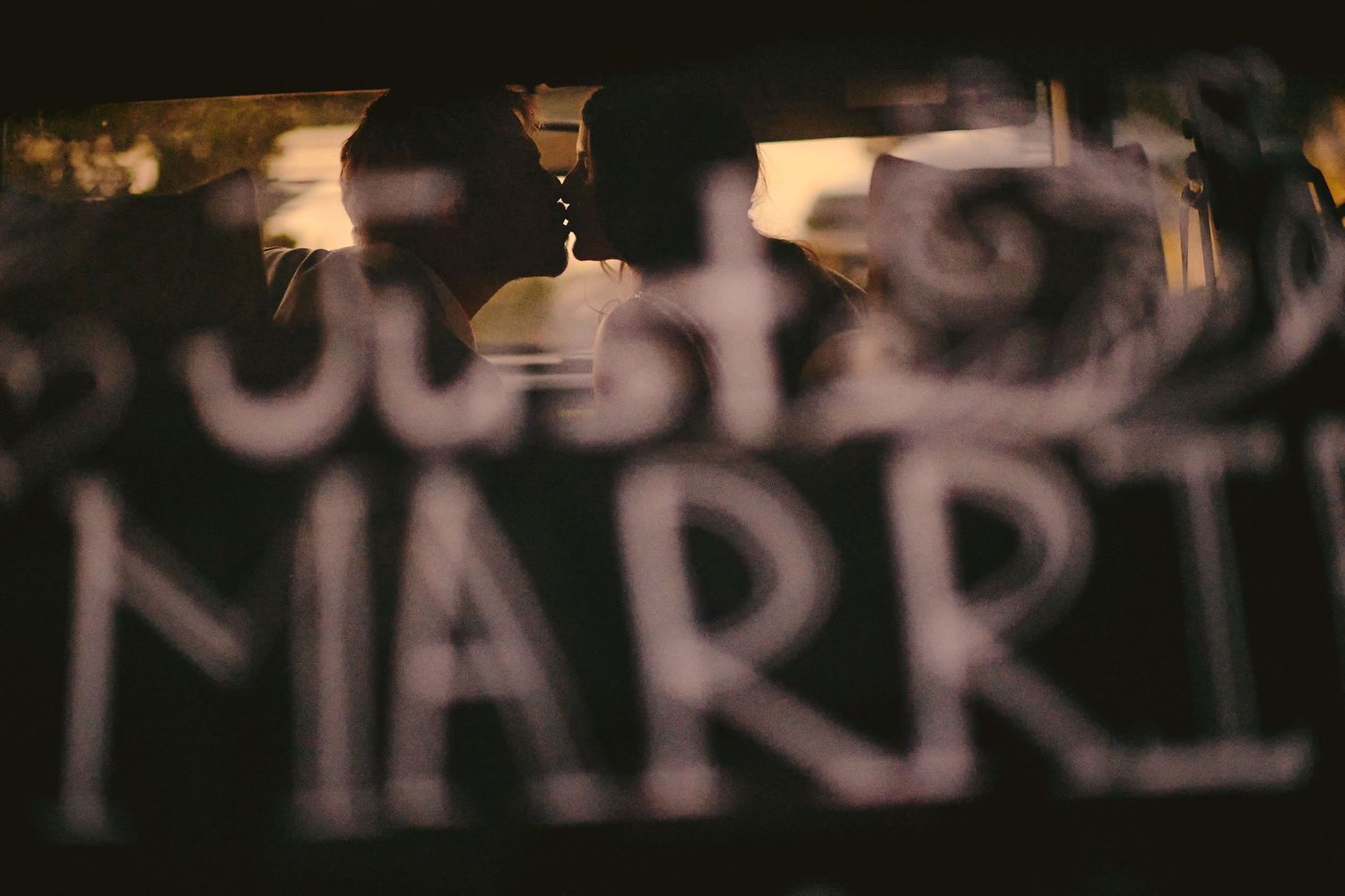 Blurred photograph of text in neon lights with a champagne glass silhouette visible against a dark background.