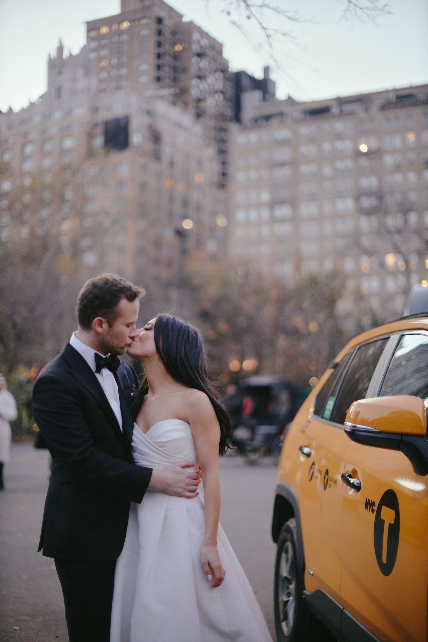 A romantic wedding moment on a New York City street with a yellow taxi cab and tall buildings in the background.
