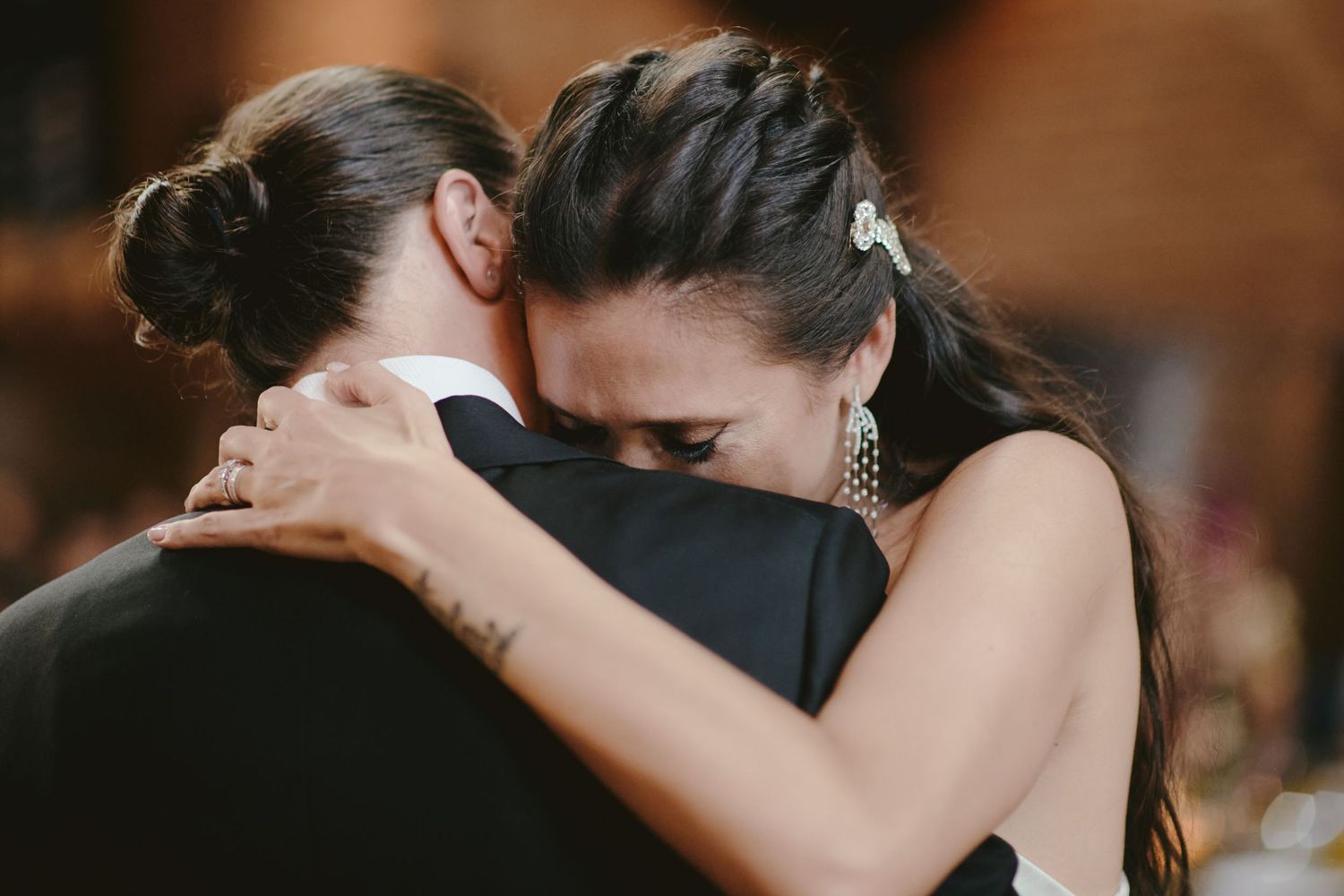 Two people share an intimate embrace while slow dancing at a formal event.