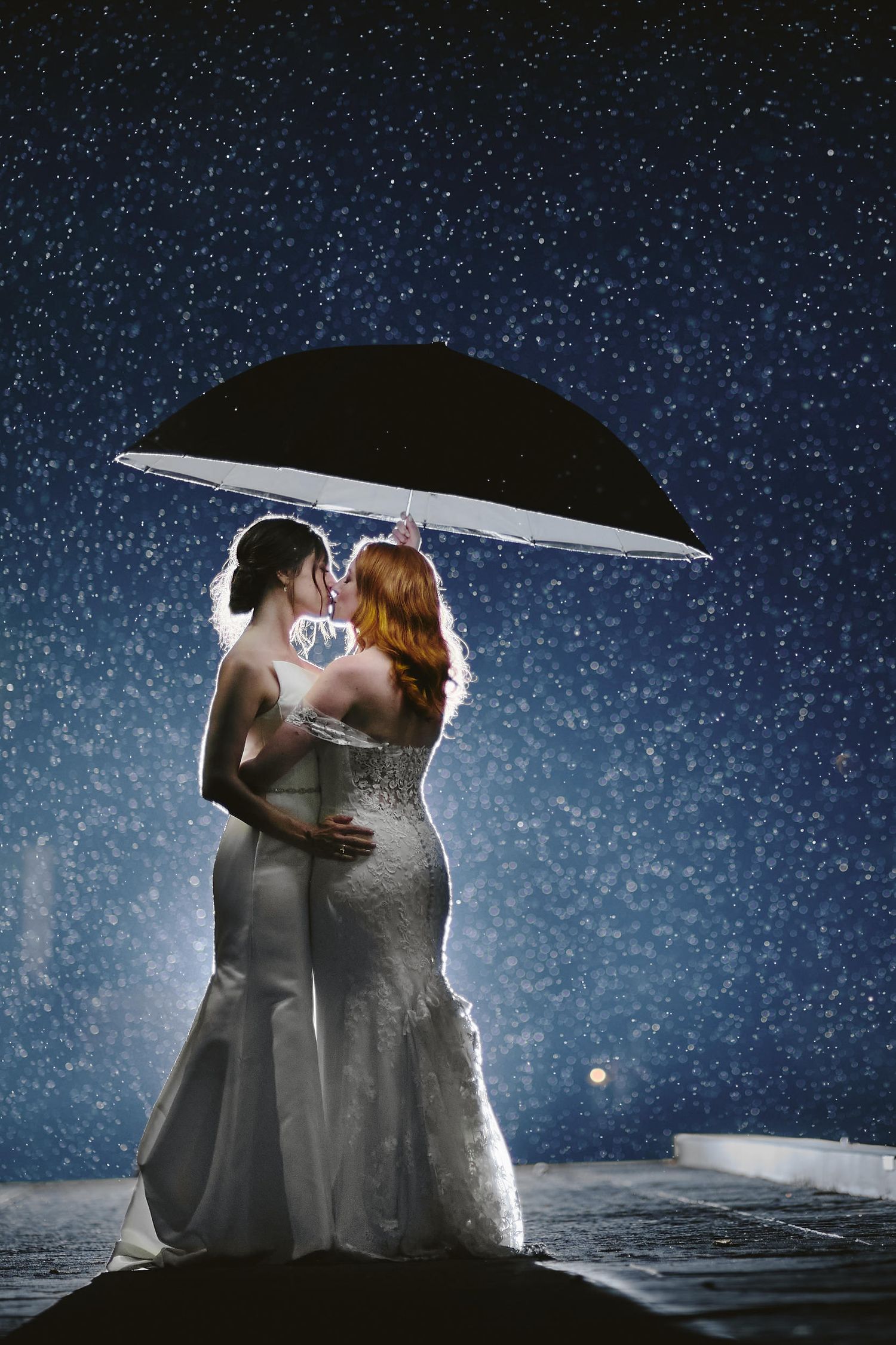Two figures share a tender moment under an umbrella against a starry night sky backdrop.