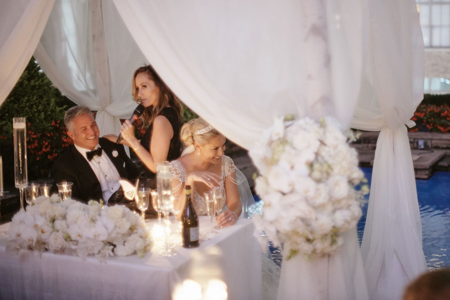 Elegant reception table with white floral arrangements and candlelight during an indoor wedding celebration.