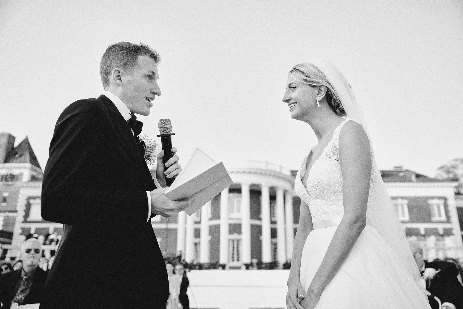 A black and white candid wedding scene with a couple sharing emotional vows outdoors.