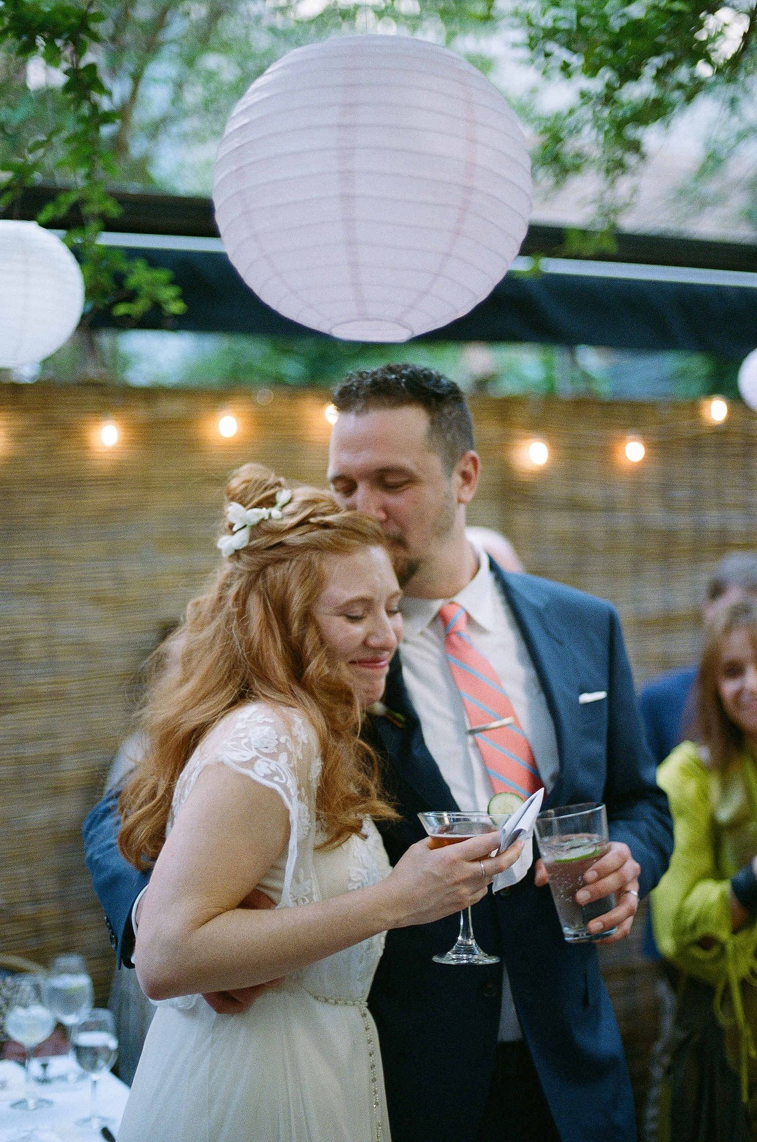 A romantic outdoor wedding reception with white paper lanterns and string lights decorating the space.