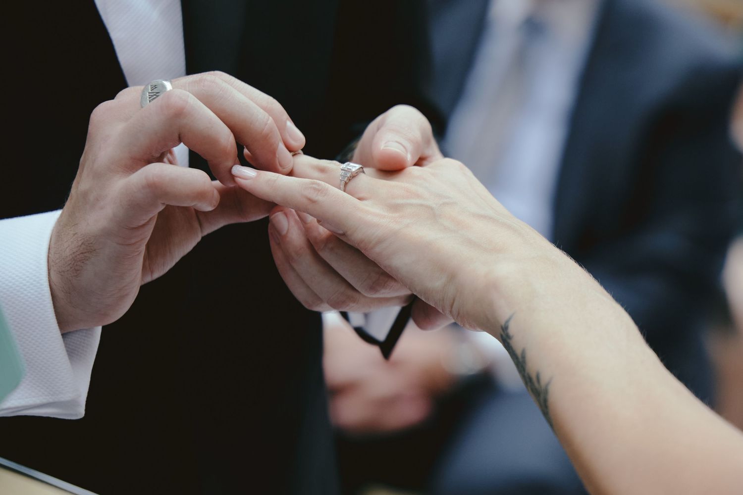 Close up of hands exchanging wedding rings during marriage ceremony.