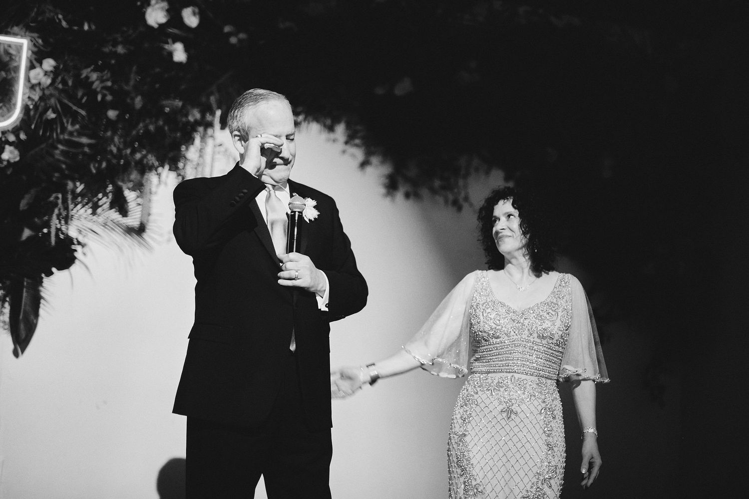 Black and white photo showing an emotional moment with speakers during a celebration at a formal event.