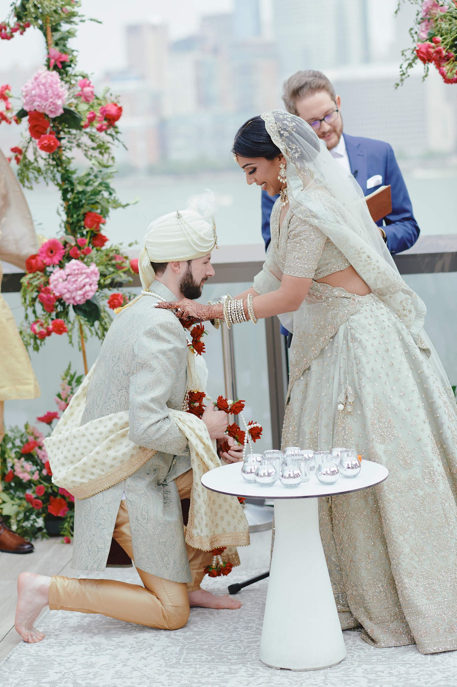 Traditional Indian wedding ceremony with floral decorations and decorative outfits during an intimate rooftop celebration.