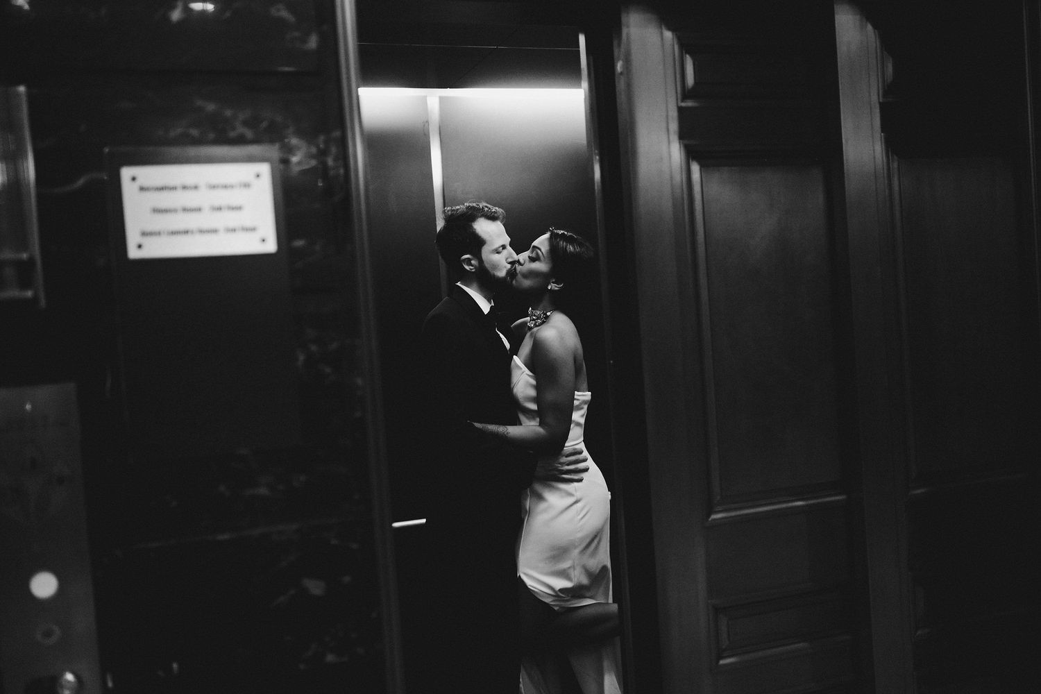 A romantic black and white photo of a couple embracing in an elevator.