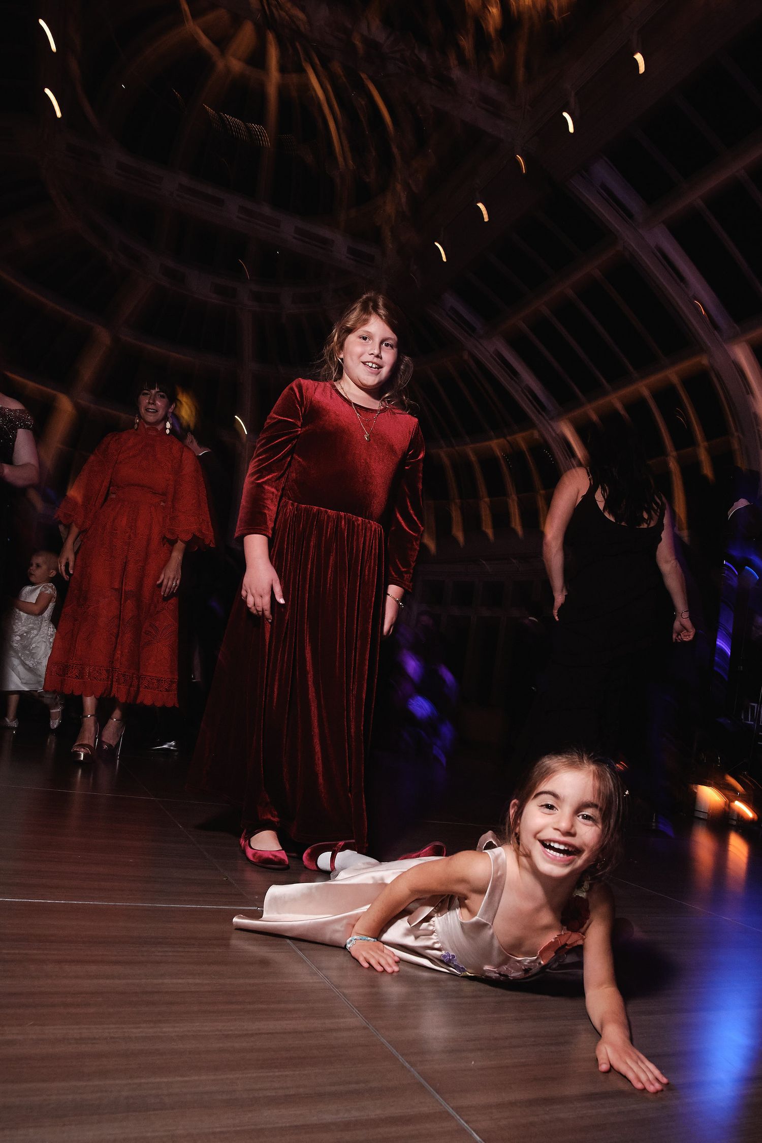 Two people enjoying themselves on a wooden dance floor at an indoor venue with atmospheric lighting.