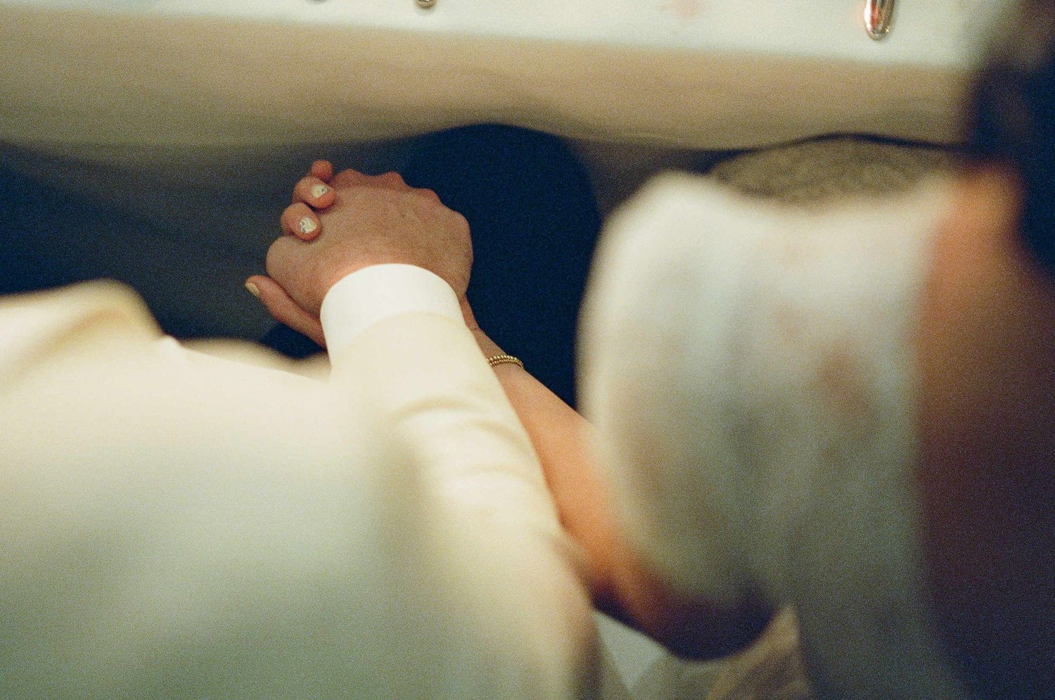Intimate close-up of hands gently clasped together in warm lighting.