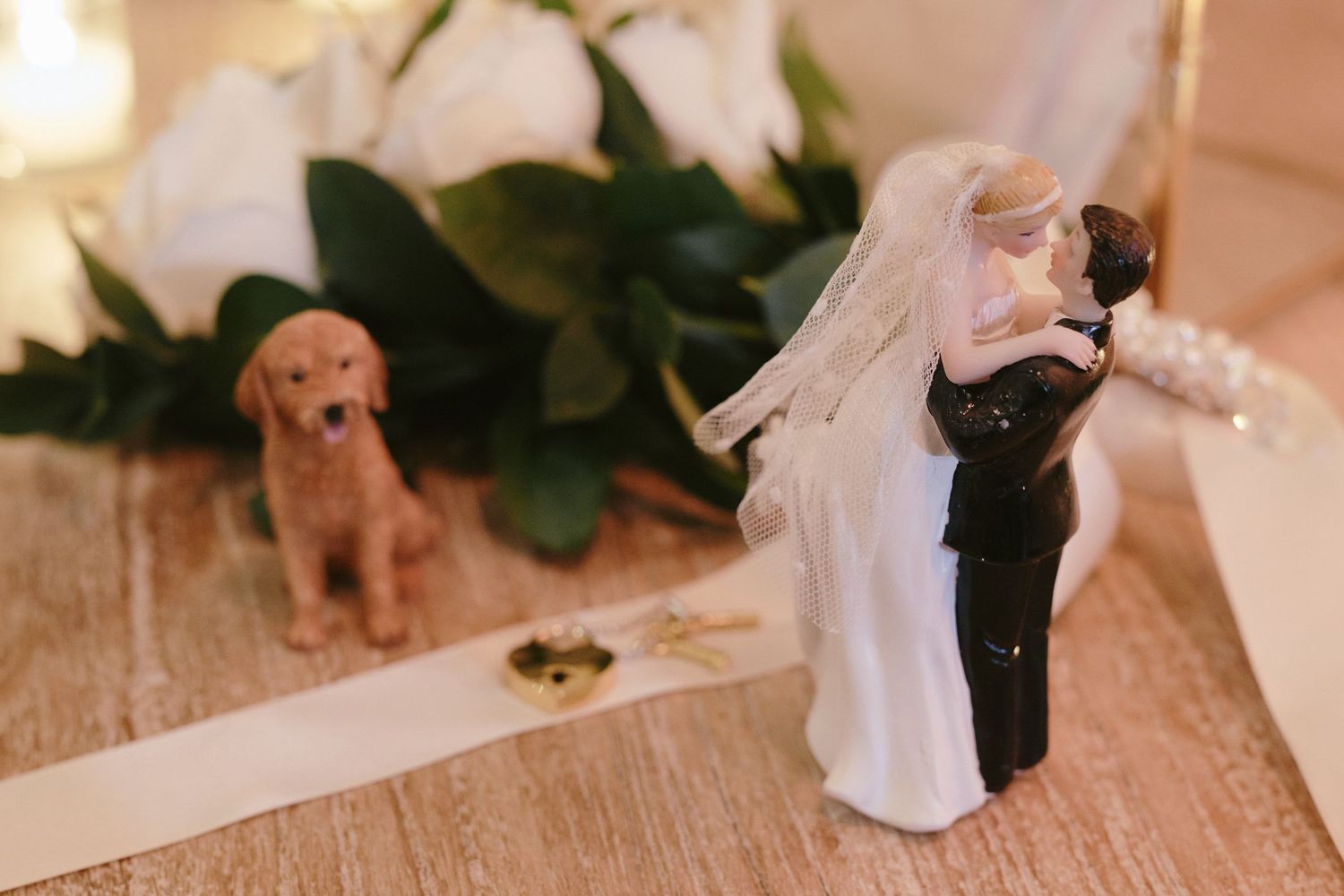 Wedding cake topper figurines with a decorative golden retriever dog statue on wooden surface.