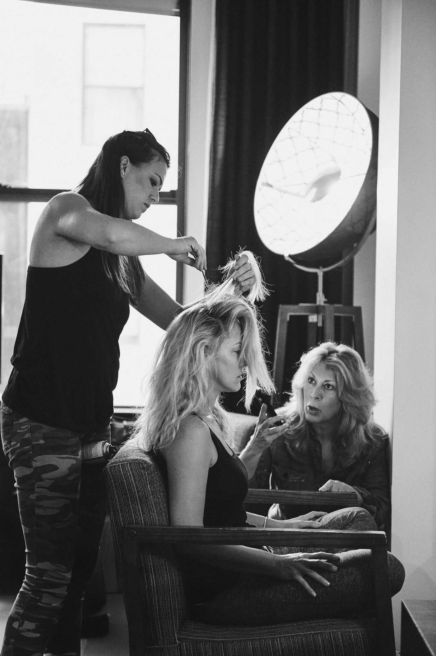 Behind the scenes photo of hair styling session with professional equipment and styling chair in black and white.