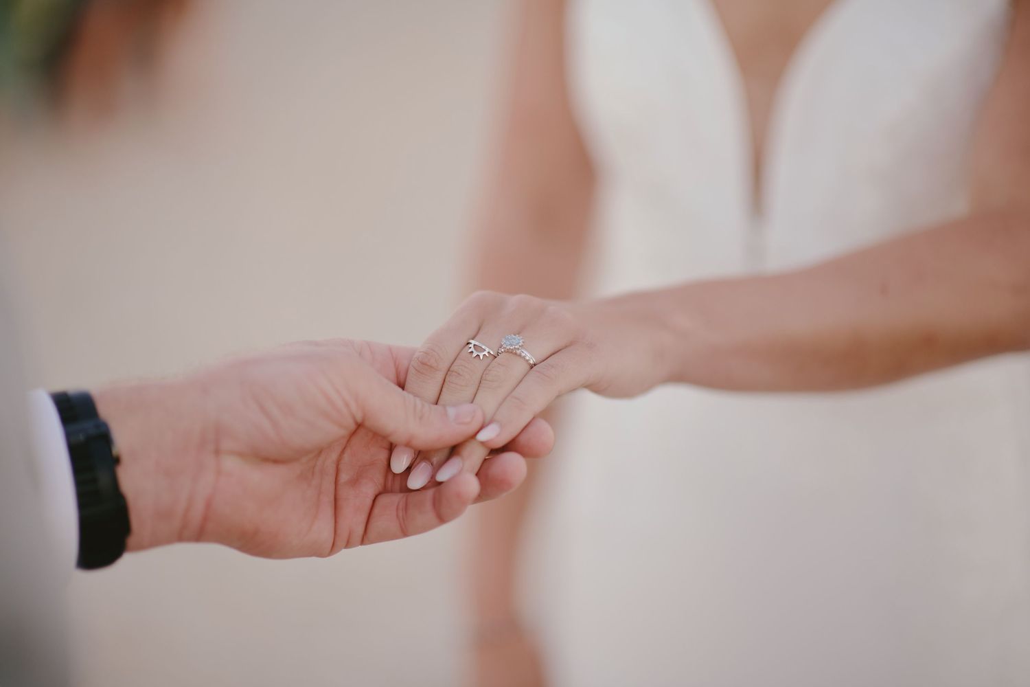 A close-up shot of hands wearing rings exchanging tender touch during a wedding ceremony.