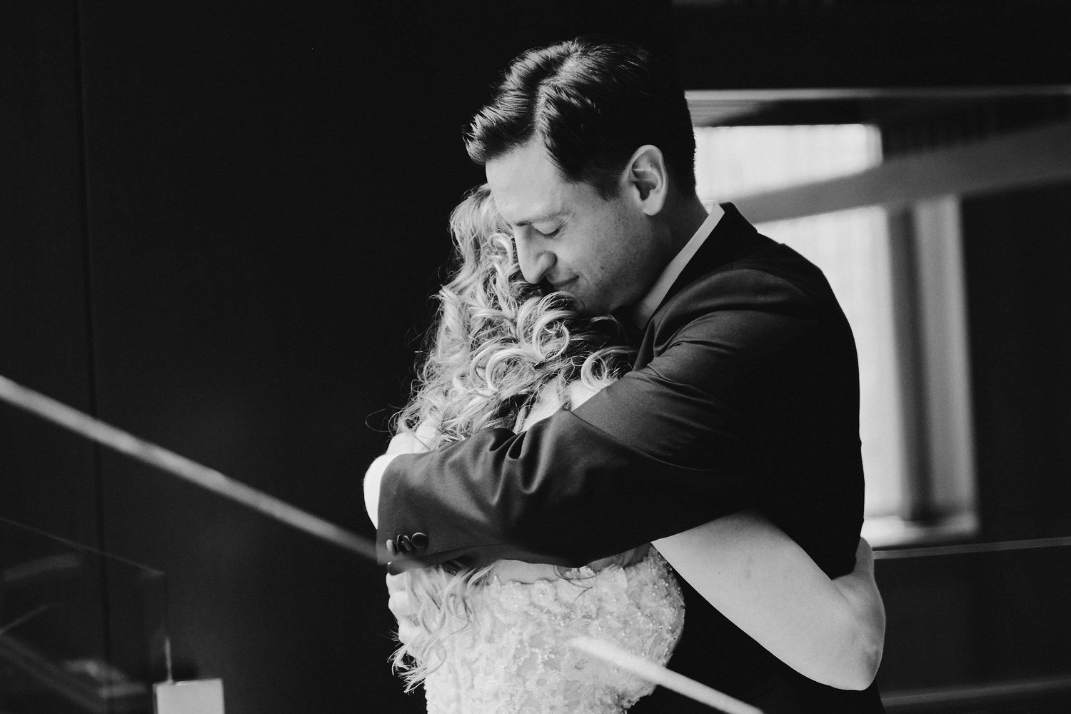A couple shares an intimate embrace during a black and white wedding moment.
